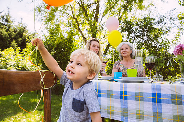boy at table with family of three generations in garden - garden decoration stock pictures, royalty-free photos & images