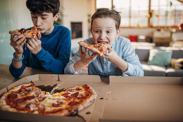 boys eating pizza together - junk food stock pictures, royalty-free photos & images