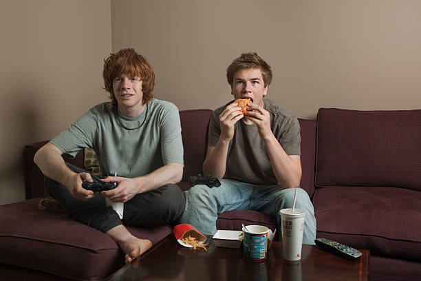 boys playing video games - junk food stock pictures, royalty-free photos & images