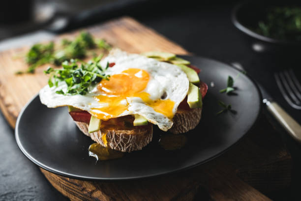 breakfast toast with avocado, fried egg and sprouts - food stock-fotos und bilder