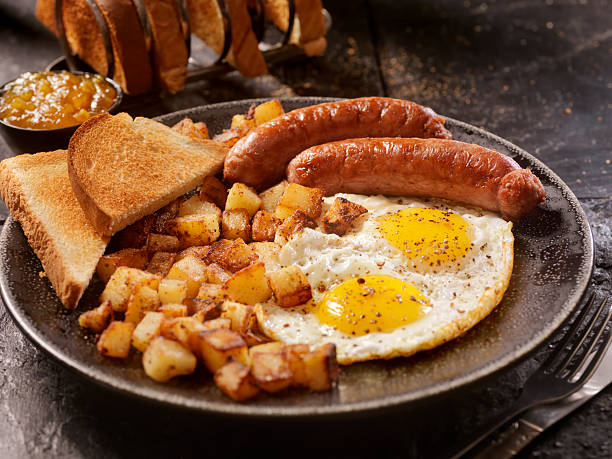 breakfast with sunny side up eggs and sausage - food stock pictures, royalty-free photos & images