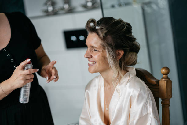 bride getting ready for wedding with stylist using hairspray and curlers - hairstyle stock pictures, royalty-free photos & images