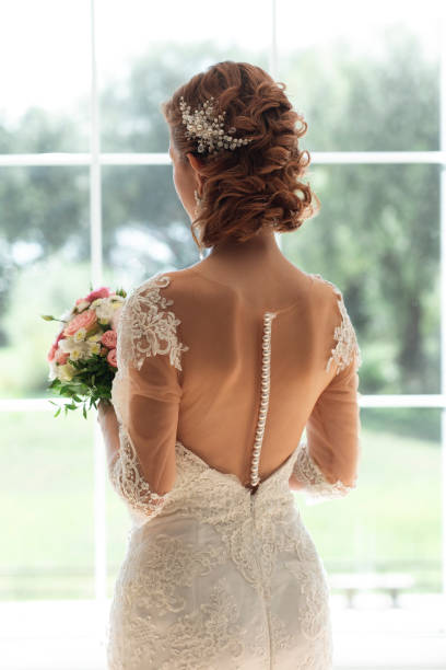 bride with bouquet by window - hairstyle stock pictures, royalty-free photos & images