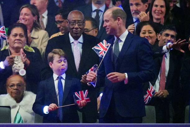 Britain's Prince George of Wales reacts as his father Britain's Prince William, Prince of Wales plays with a Union flag during the Coronation Concert...