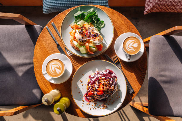 brunch with sweet pancakes and eggs benedict with salmon served in restaurant - food stock pictures, royalty-free photos & images