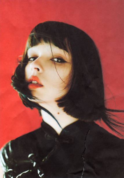 brunette asian woman in studio on red background. fashion model. scanned film photo. dust and scratches on photo. - fashion stock pictures, royalty-free photos & images