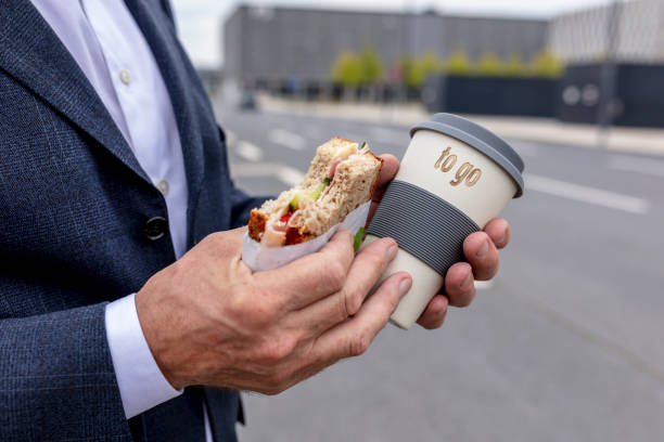 business man is eating while lunch break on the go - junk food stock pictures, royalty-free photos & images