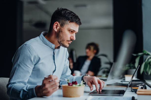 businessman having a lunch break at desk in the office - junk food stock pictures, royalty-free photos & images