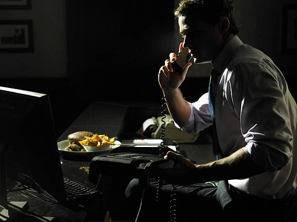 businessman using phone, take away meal on desk, night - junk food stock pictures, royalty-free photos & images