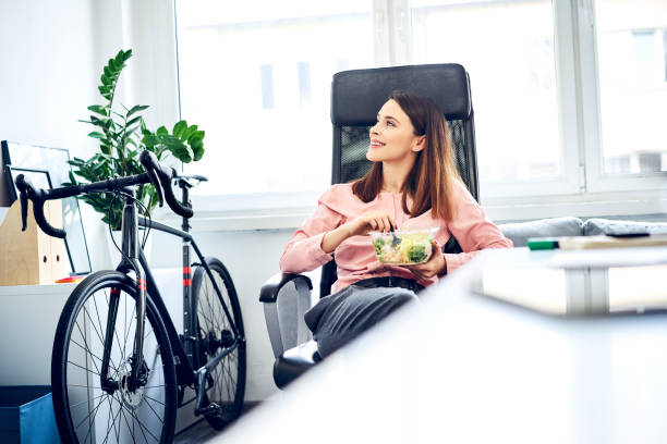 businesswoman having lunch break in office sitting at desk - junk food stock pictures, royalty-free photos & images