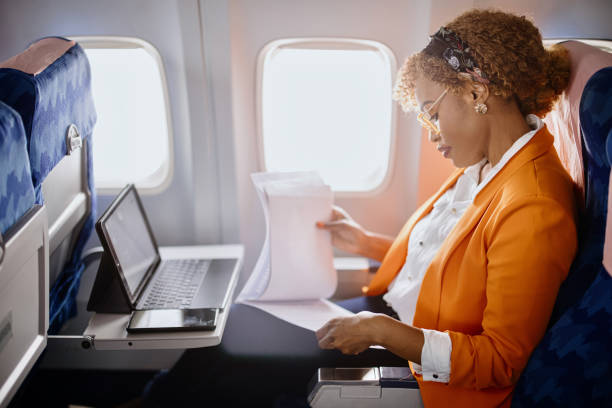 businesswoman reading documents and working on digital tablet during flight - travel stock pictures, royalty-free photos & images