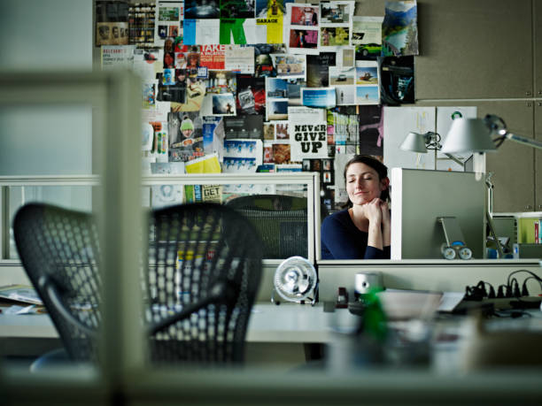 businesswoman sitting at desk in office smiling - home decoration stockfoto's en -beelden