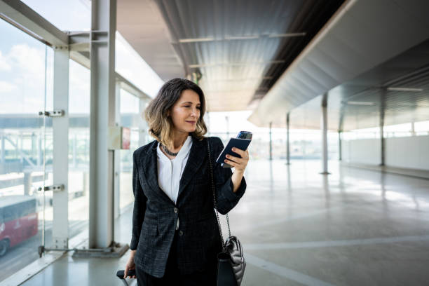 businesswoman walking while use phone at the airport - travel stock pictures, royalty-free photos & images