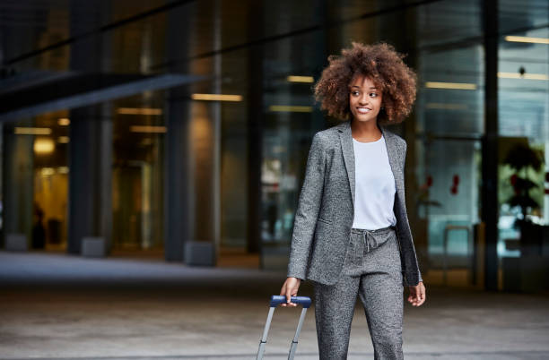 businesswoman with luggage walking outside office - travel stock pictures, royalty-free photos & images