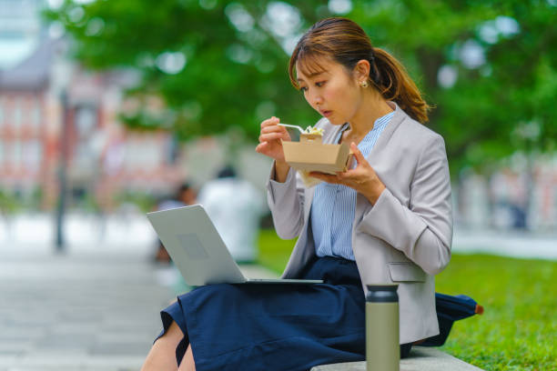businesswoman working on laptop while having lunch in the city - junk food stock pictures, royalty-free photos & images