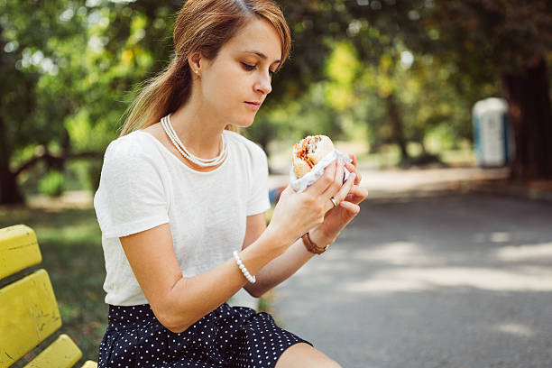 busy woman eating hamburger outside the office - junk food stock pictures, royalty-free photos & images