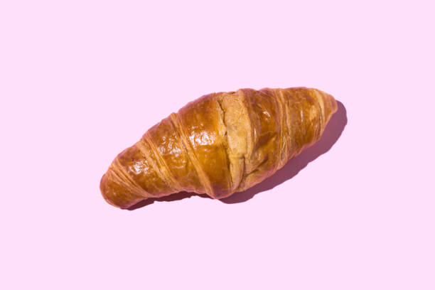 butter croissant with hard shadow on pink background. industrial pastry concept, calories, fattening, fat, cholesterol, delicious, sugar - junk food stock pictures, royalty-free photos & images