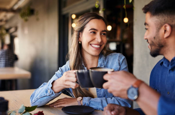 cafe, couple date cheers and woman smile in a coffee shop with a man feeling love and happiness. restaurant, discussion and happy people out for lunch talking about relationship with morning drink - coffee stock pictures, roy