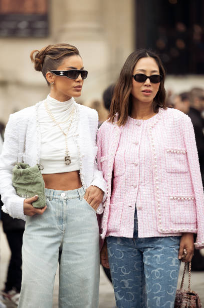Camila Coelho wears mint green jeans, white turtleneck cropped top, white jacket, green bag and sunglasses and Aimee Song wears blue jeans, pink...