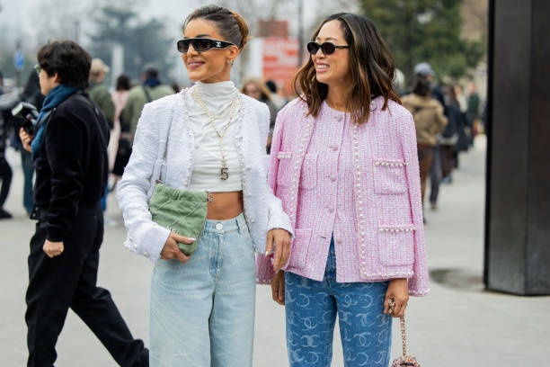 Camila Coelho wears white cropped turtleneck, jacket, denim jeans, green bag, necklace, sunglasses & Aimee Song wears pink button up blouse, jacket,...