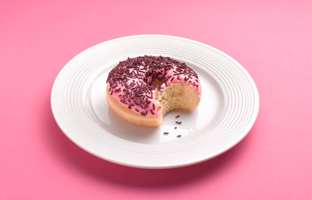 can't resist temptation bite out of doughnut - junk food stock pictures, royalty-free photos & images