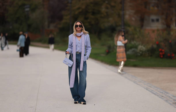 Candela Pelizza is seen wearing a lilac color long scarf, a purple cardigan, baggy blue jeans, Chanel black lace ballerinas, a purple Chanel Classic...