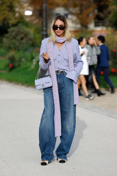 Candela Pelizza wears lilac tweed Chanel jacket, blue jeans, black Chanel belt, lilac knitted scarf, lilac Chanel bag, black sunglasses, Chanel...