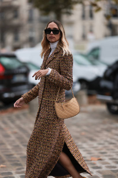 Candela Pelizzais seen outside Chanel show wearing black Chanel sunnies, white shirt underneath, beige and black checkered Chanel coat, black and...