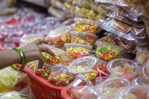 candy store front with colorful candies and sugar coated fennel being picked up by a kid. - junk food stock pictures, royalty-free photos & images