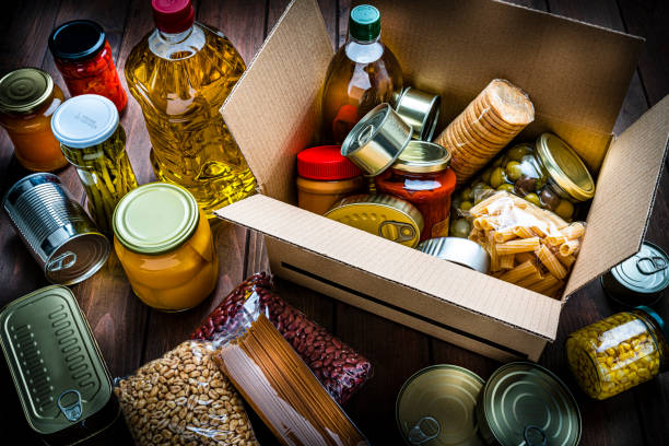 cardboard box filled with non-perishable foods on wooden table. high angle view. - food stock pictures, royalty-free photos & images