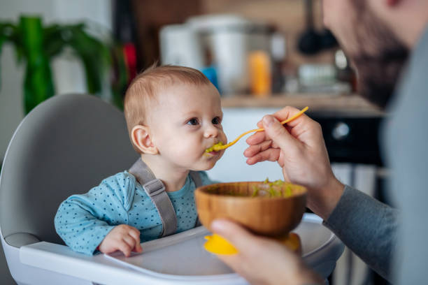 caring single father spoon feeding his beautiful son. - food stock pictures, royalty-free photos & images