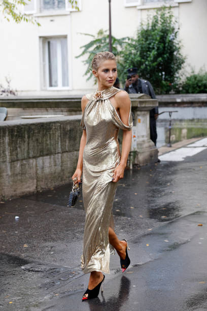 Caro Daur wears gold long dress, black Rabanne bag, black sandals, outside Rabanne, during Womenswear Spring/Summer 2025 as part of Paris Fashion...