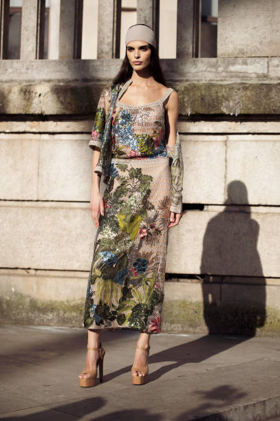 Carol Mendes wears beige and multicolour sheer knitted sequin top with with matching skirt and short sleeve blouse or sweater and beige bandana...