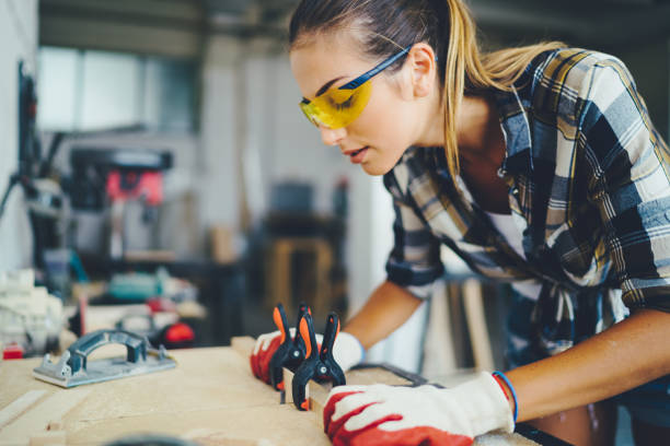 carpenter woman at work using electric saw to cut timber - home decoration stock pictures, royalty-free photos & images