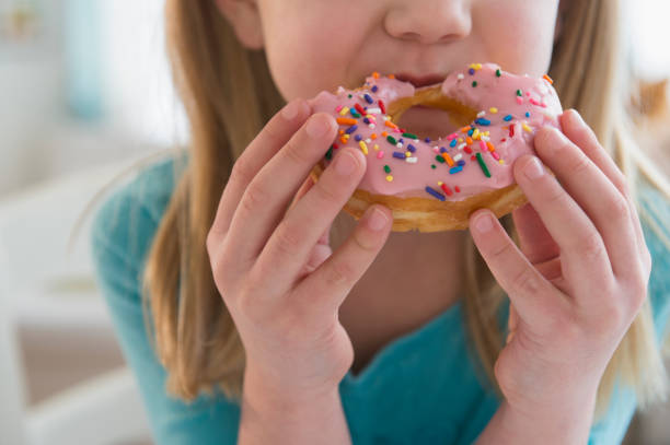 caucasian girl eating donut - junk food stock pictures, royalty-free photos & images