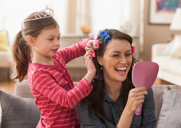 caucasian mother and daughter playing dress up - hairstyle stockfoto's en -beelden