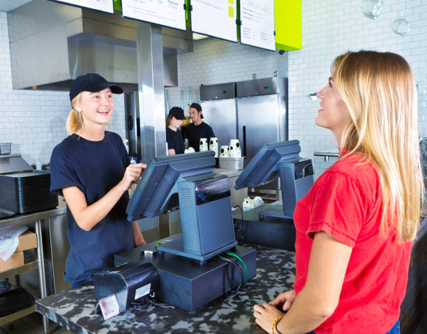 checkout server serving young woman customer ordering at fast food restaurant - junk food stock pictures, royalty-free photos & images
