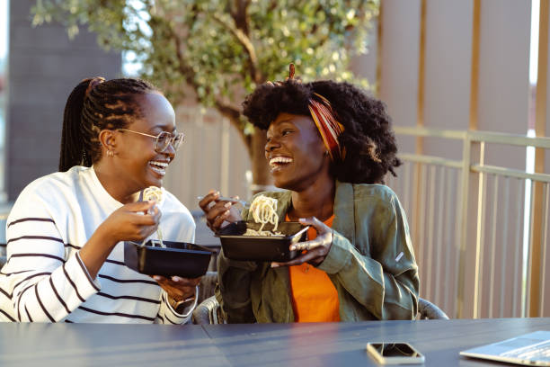 cheerful african american female friends eating fast food meal in the city - junk food stock pictures, royalty-free photos & images
