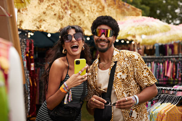 cheerful couple trying sunglasses at market stall - concert stock pictures, royalty-free photos & images