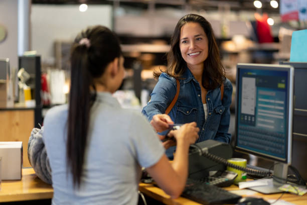 cheerful female customer making a contactless payment with credit card at a furniture store smiling - home decoration stock pictures, royalty-free photos & images