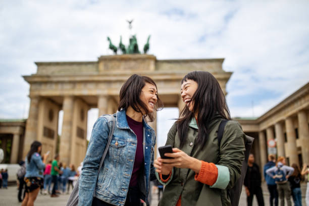 cheerful friends standing against brandenburg gate - travel stock pictures, royalty-free photos & images