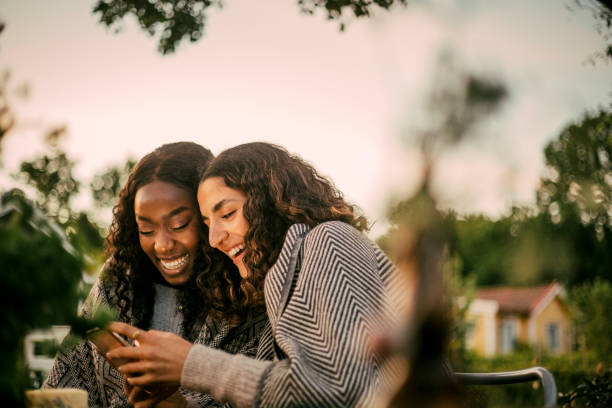 cheerful friends using phone in backyard during social gathering - garden decoration photos et images de collection