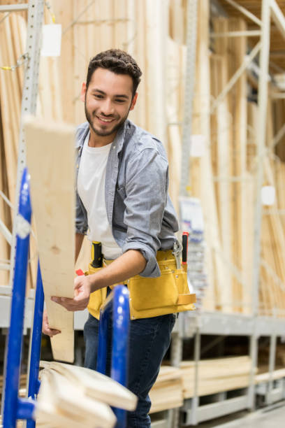 cheerful lumber yard worker loads planks on a dolly - home decoration stock pictures, royalty-free photos & images