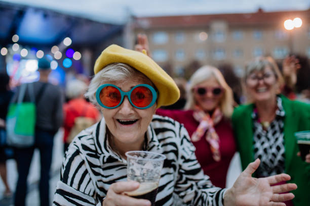 cheerful senior friends enjoying outdoor night concert in city. - concert stock pictures, royalty-free photos & images