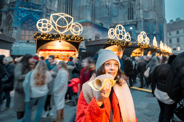 cheerful woman eating a pastry dough at christmas markets, vienna, austria - junk food stock pictures, royalty-free photos & images