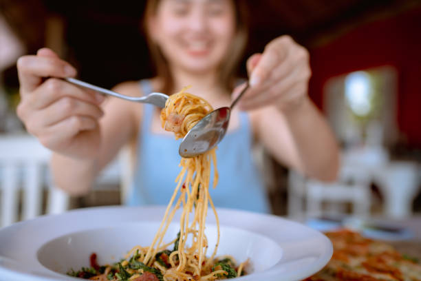 cheerful woman eating spicy spaghetti at restaurant. - food stock pictures, royalty-free photos & images