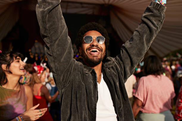 cheerful young man dancing with arms raised near girlfriend - concert stock pictures, royalty-free photos & images