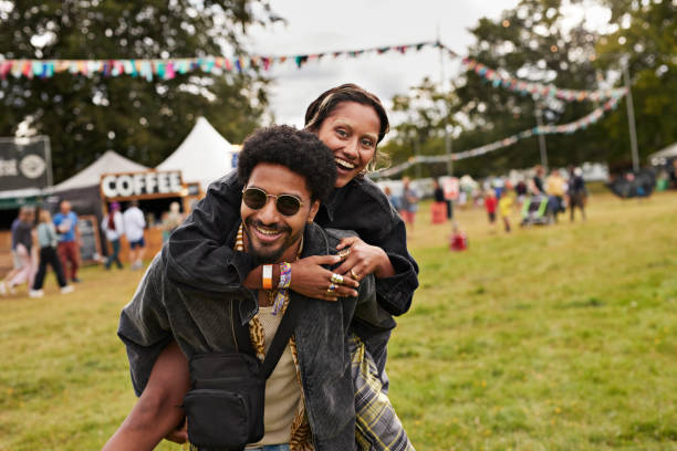 cheerful young man giving piggyback to girlfriend - concert stock pictures, royalty-free photos & images