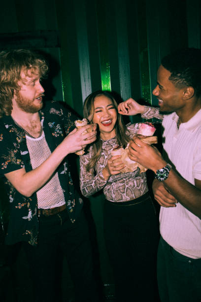 cheerful young multiracial friends eating wrap sandwiches together at nightclub - concert stock pictures, royalty-free photos & images