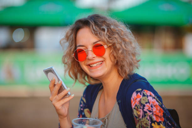cheerful young woman with red sunglasses and phone - concert stock pictures, royalty-free photos & images